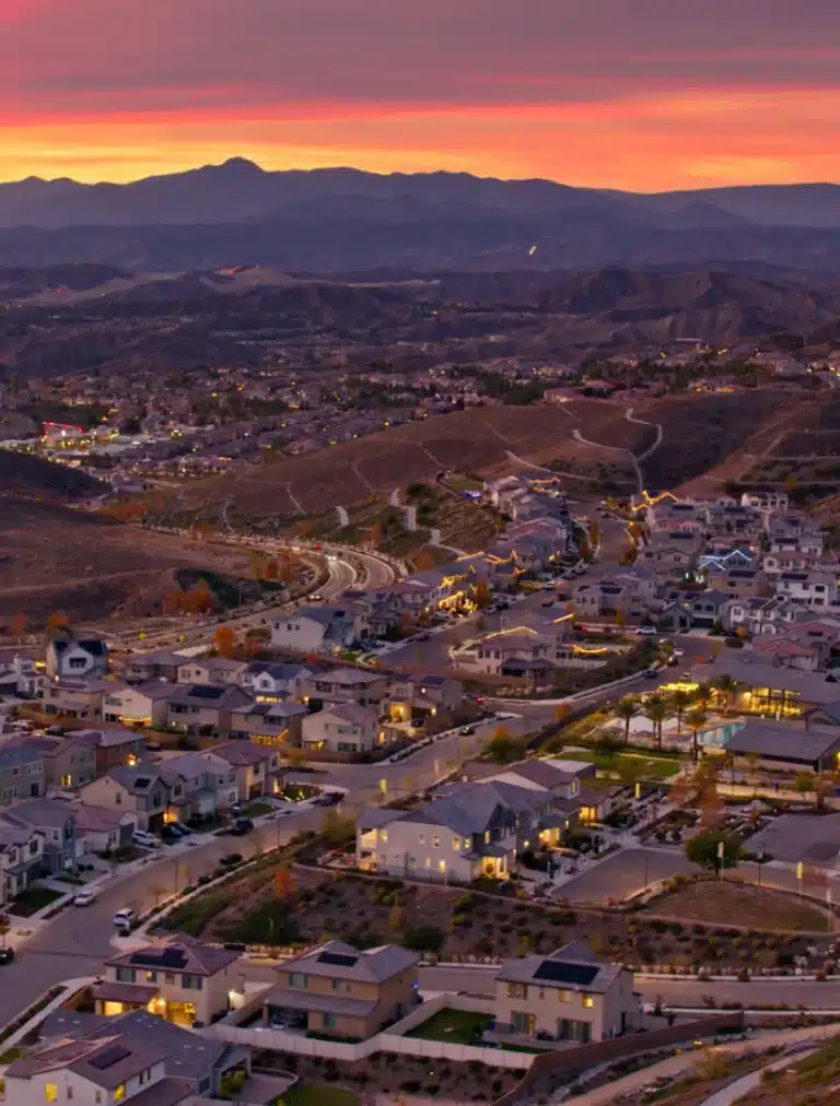 A vibrant cityscape of Santa Clarita, California, showing modern buildings surrounded by scenic hills under a clear blue sky, representing the mix of urban life and natural beauty the city is known for.