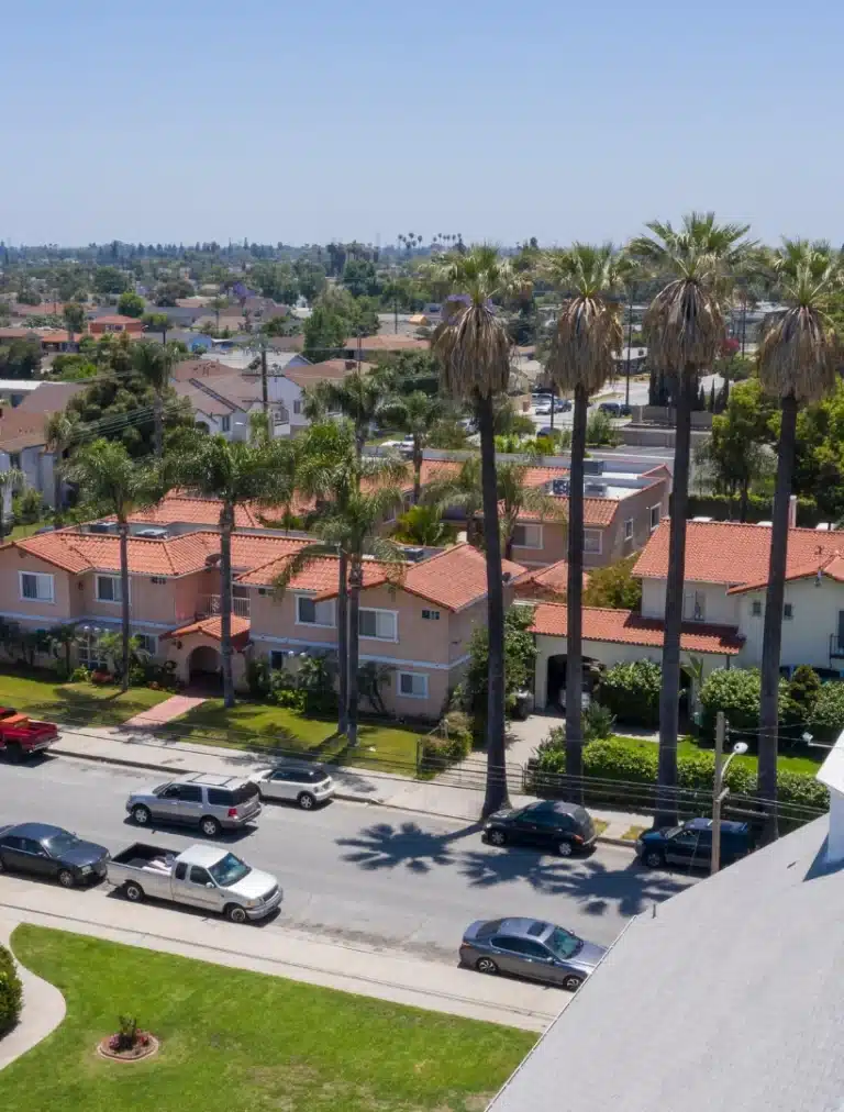 Residential neighborhood with red-tile roof homes, tall palm trees, and a sunny street in Pico Rivera, CA.